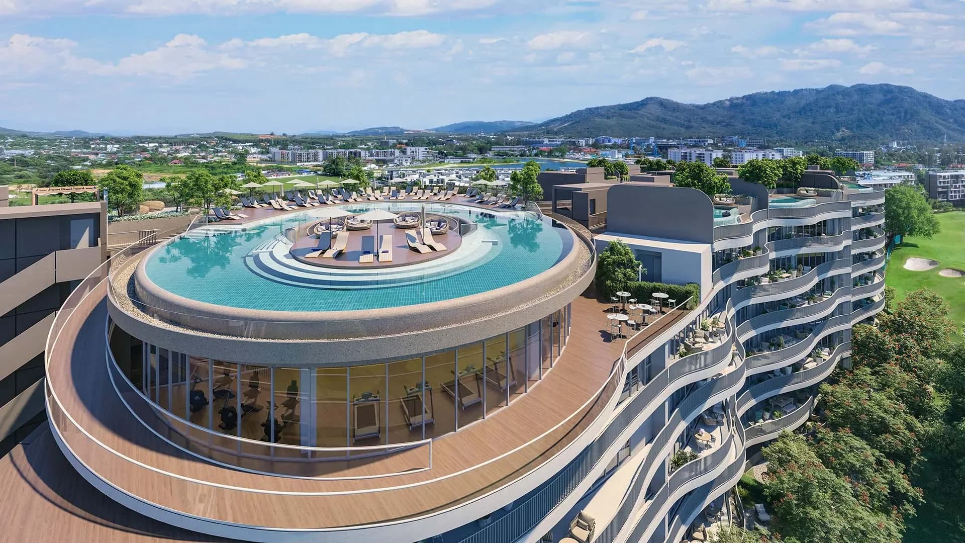 The ring-shaped rooftop pool above the curved buildings, with Laguna Golf and the mountains behind